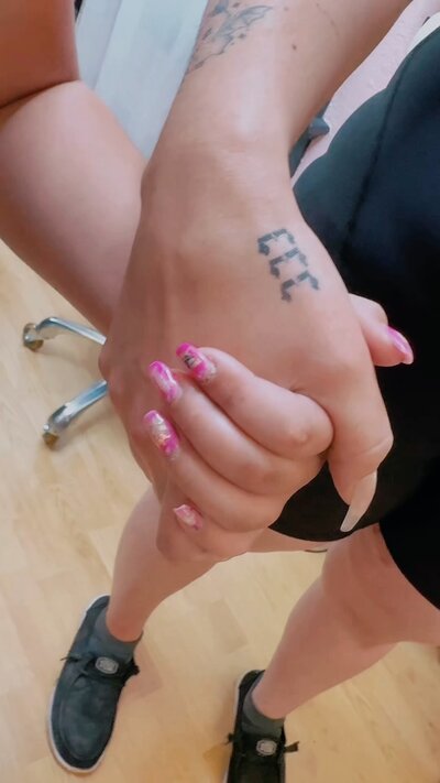 Matching hand-holding fine line tattoo, a mother-daughter design.